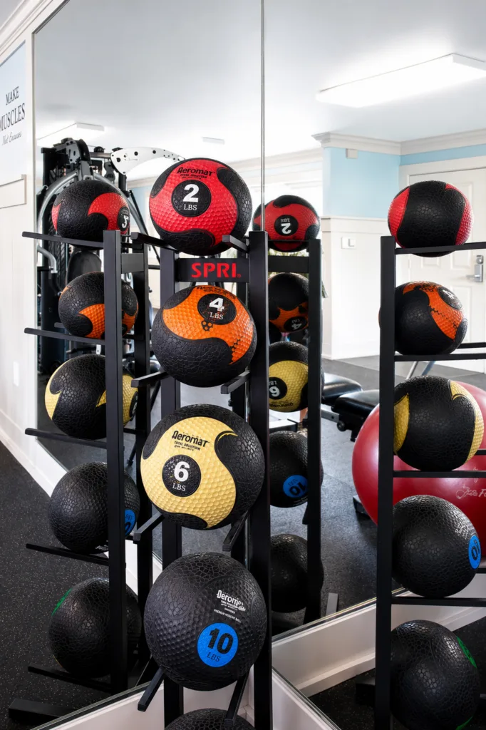 Rack of colorful weighted medicine balls in a gym, reflected in a wall mirror